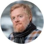 Headshot of a man with beard wearing a scarf and plaid shirt